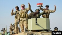 Iraqi forces show victory signs after they captured Rawa town, the last remaining town under Islamic State control, Nov. 17, 2017. 