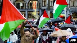 FILE —Protesters hold Palestinian flags as they take part in the Red March to call for a ceasefire in the Gaza Strip, in Amsterdam on November 18, 2023.