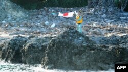 A Japanese activist waves the country's flag after landing on a group of islands known as Senkaku in Japanese and Diaoyu in Chinese, August 19, 2012.