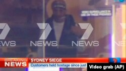 FILE - This image taken from video shows a man believed to be a gunman inside a cafe in Sydney, Australia, Dec. 15, 2014. 