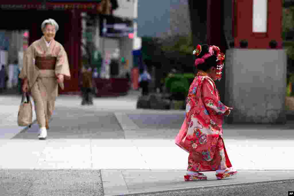 A child in a colorful kimono strolls along the sidewalk in Tokyo&#39;s Asakusa district. Japan, during the Shichigosan celebration.