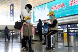 Travelers wearing face masks and goggles to protect against the spread of new coronavirus sit at Wuhan Tianhe International Airport in Wuhan in central China's Hubei Province, April 8, 2020.