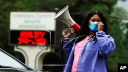 In this May 27, 2020, photo, health care worker Tonya Wilkes adjusts her mask while working at a Lowndes County coronavirus testing site in Hayneville, Ala.