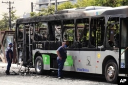 Police inspect a bus that caught fire after a small aircraft crashed on an avenue in Sao Paulo, Feb. 7, 2025.