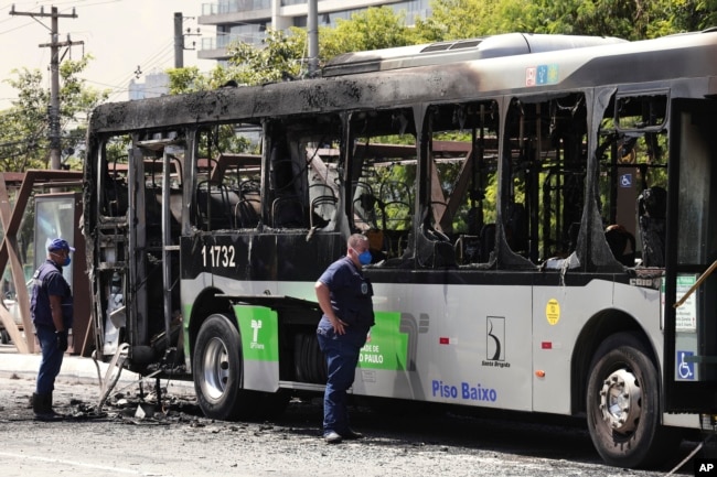 Polisi memeriksa bangkai bus yang sebelumnya terbakar setelah terkena bagian pesawat kecil yang jatuh di sebuah jalan raya di Sao Paulo, Brazil, Jumat, 27 Februari 2025. (Foto: Ettore Chiereguini/AP Photo)