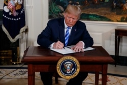 FILE - President Donald Trump signs a Presidential Memorandum on the Iran nuclear deal from the Diplomatic Reception Room of the White House, May 8, 2018.