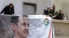 Syrians, including members of the Syrian National Defense Forces (NDF), hang a portrait of President Bashar al-Assad on June 13, 2015 in the ancient Christian town of Maalula.