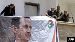 Syrians, including members of the Syrian National Defense Forces (NDF), hang a portrait of President Bashar al-Assad on June 13, 2015 in the ancient Christian town of Maalula.