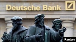 Sebuah patung di sebelah logo Deutsche Bank di Frankfurt, Jerman, 30 September 2016.