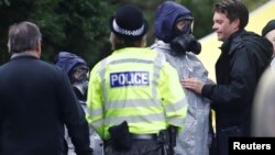 Polisi Inggris mengenakan masker pelindung saat memeriksa lokasi kuburan Luidmila Skripal, istri mantan mata-mata Rusia Sergei Skripal di Salisbury, Inggris (10/3). 