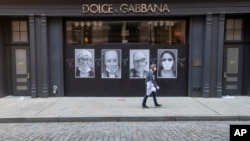 ຊາຍຄົນນຶ່ງທີ່ໃສ່ໜ້າກາກ ປະທ້ວງໄວຣັສໂຄໂຣນາ ຍ່າງຜ່ານຮ້ານ Dolce & Gabbana ທີ່ຖືກປິດ ໃນວັນພະຫັດ ທີ 7 ພຶດສະພາ ປີ 2020.