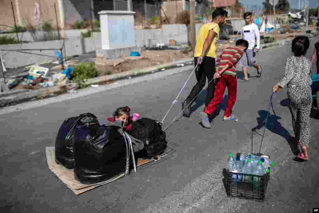 Migrants pull a child and their belongings in Kara Tepe, near Mytilene, the capital of the northeastern island of Lesbos, Greece.