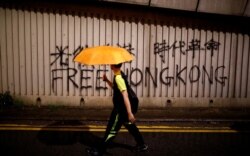 A man walks past a graffiti during a march to demand democracy and political reforms in Hong Kong, China, Aug. 18, 2019.