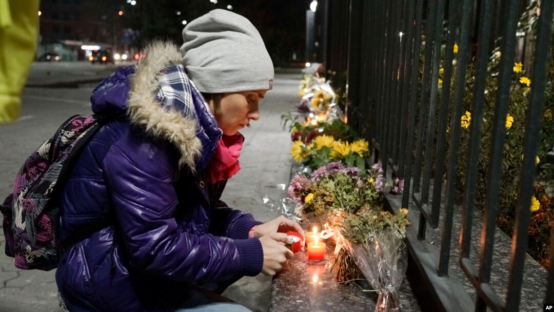 A Ukrainian woman lights a candle in front of the Russian Embassy in Kyiv to pay tribute to victims of a Russian plane crash in the Sinai Peninsula, Oct. 31, 2015.