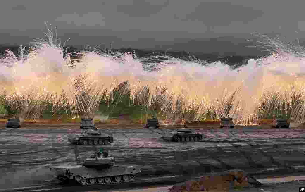 Japan Ground Self-Defense Force&#39;s Type-89 armored combat vehicles flare up a smoke screen during an annual live firing exercise at Higashi Fuji range in Gotemba, southwest of Tokyo.