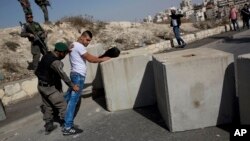 FILE - Israeli border police search a Palestinian, next to newly placed concrete blocks in an east Jerusalem neighborhood, Oct. 15, 2015. Israeli police say they have arrested several young members of a Jewish terrorist group suspected of carrying out a July arson attack that killed three Palestinians.