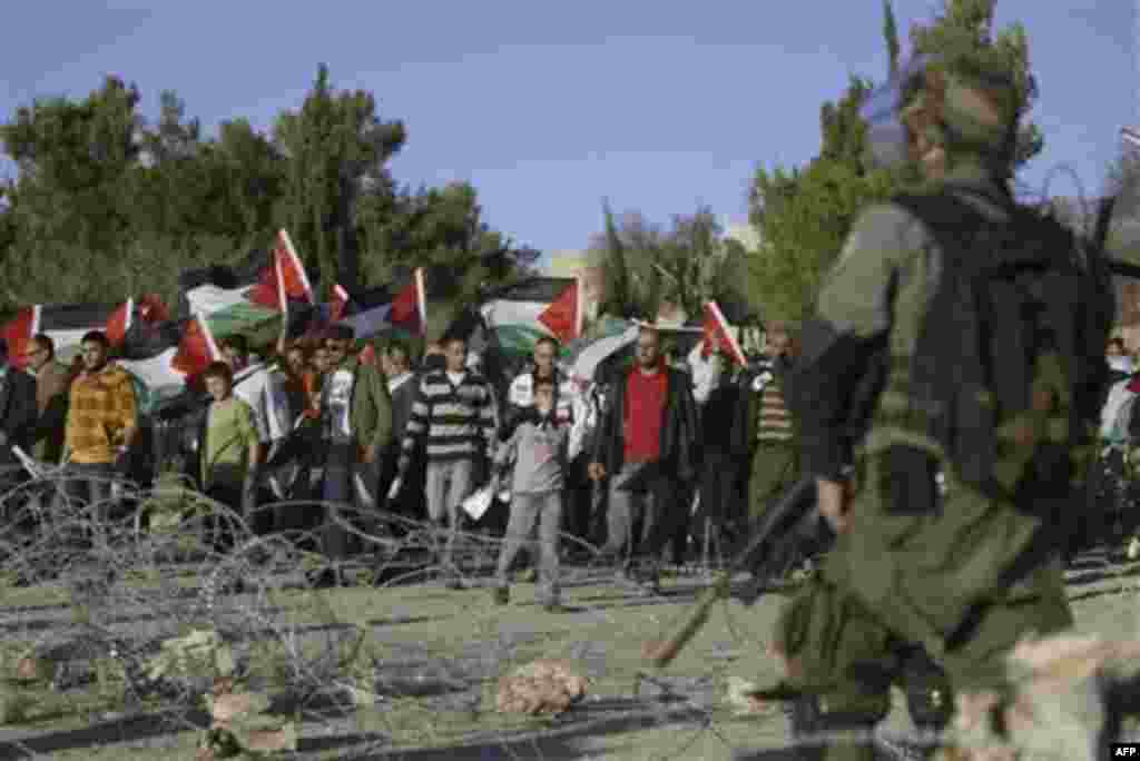 Palestinian and foreign activists hold Palestinian flags near Israeli soldiers during a protest against an Israeli roadblock at the entrance to the West Bank village of Beitin, near Ramallah, Monday, Dec. 27, 2010. (AP Photo/Majdi Mohammed)