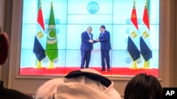 Arab reporters watch a screen displaying Egyptian President Abdel Fattah el-Sissi, right, receiving Palestinian Authority President Mahmoud Abbas at the press center hall of the emergency Arab summit just outside Cairo on March 4, 2025.