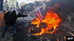 Demonstran Palestina membakar bendera AS dalam aksi protes terhadap keputusan Presiden Donald Trump untuk mengakui Yerusalem sebagai ibu kota Israel, di Beit El, Tepi Barat Kamis (7/12). 