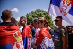 FILE - Serbs holding Serbian flags take part in a ceremony marking the historic Battle of Kosovo, at a memorial in Gazimestan, on the outskirts of Pristina, Kosovo, June 28, 2020.