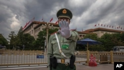A Chinese People's Liberation Army (PLA) soldier wearing a protective face mask gestures to the photographer to stop taking photos in front of the Great Hall of the People, after the second plenary session of China's National People's Congress (NPC)…