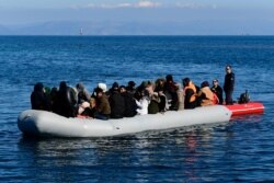 FILE - A Greek Coast Guard boat intercepts a dinghy with migrants near the Greek island of Lesbos, after it crossed the Aegean Sea from Turkey, March 1, 2020.