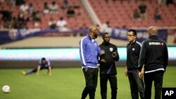 Jean-Florent Ikwange Ibenge, entraîneur-chef de Shanghai Shenhua, 2ème à gauche, discute avec Nicolas Anelka, entraîneur-joueur, à gauche, avant le match Super League chinoise entre Shanghai Shenhua et Shandong Luneng dans au stade de Shanghai Hongkou en Chine, samedi 28 Avril 2012. (AP Photo / Eugene Hoshiko)