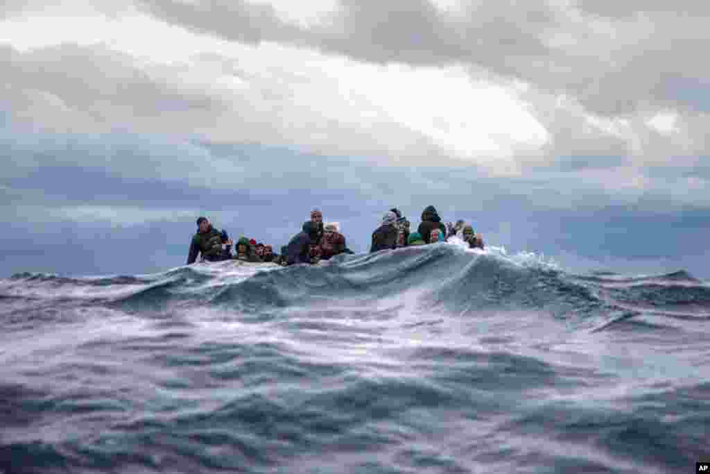 Men from Morocco and Bangladesh react on an overcrowded wooden boat, as aid workers of the Spanish NGO Open Arms approach them in the Mediterranean Sea, international waters, off the Libyan coast.