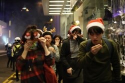 Residents dressed for Christmas festivities react to tear gas as police confront protesters on Christmas Eve in Hong Kong, Dec. 24, 2019.