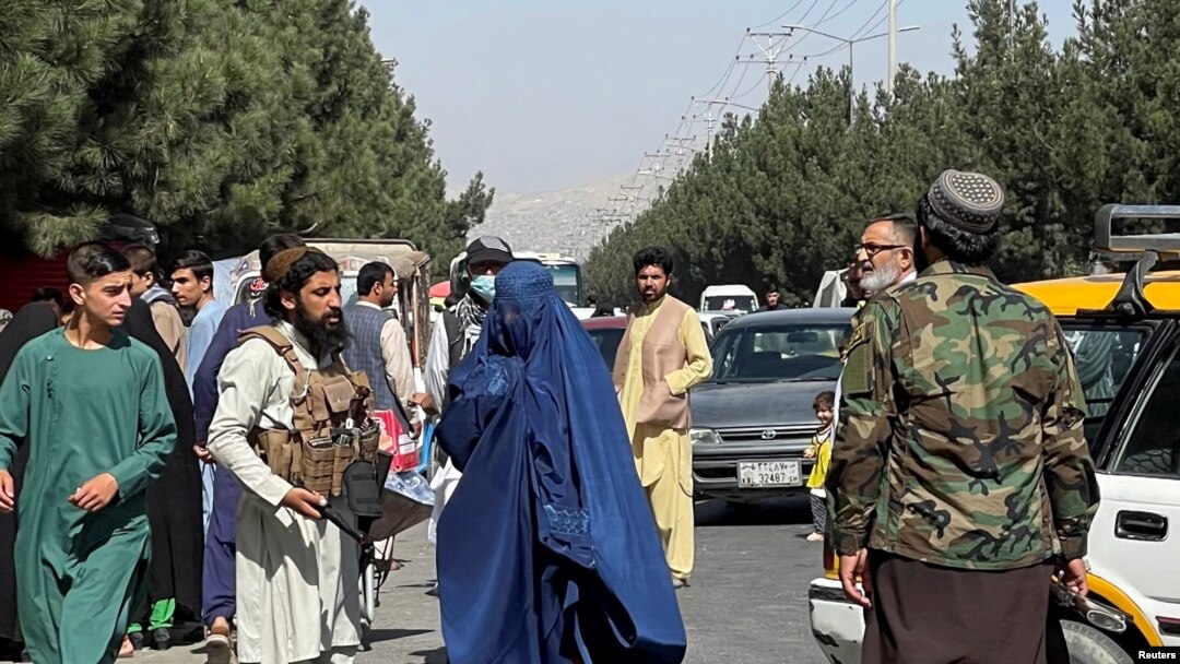 Pasukan Taliban memblokir jalan di sekitar bandara sementara seorang perempuan melintas, di Kabul, Afghanistan, Jumat, 27 Agustus 2021. (Foto: Reuters)