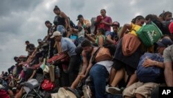 Migrants help fellow migrants onto the bed of a trailer in Jesus Carranza, in the Mexican state of Veracruz, Wednesday, Nov. 17, 2021. 