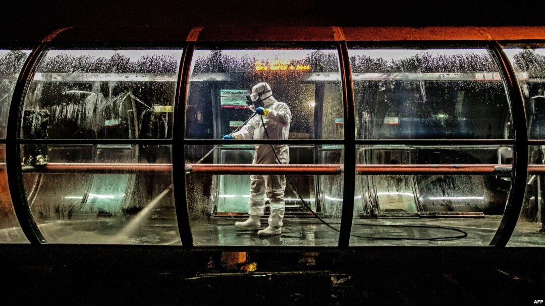 Seorang sukarelawan menyemprotkan disinfektan di terminal bus di Curitiba, Brazil, untuk mencegah penyebaran virus corona, 1 April 2020. 