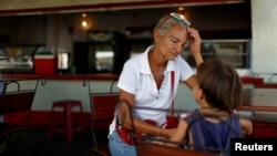 Zulay Pulgar, 43, rest in a coffee shop with her son Emmanuel, 4, after standing in line to buy cement in a hardware store in Punto Fijo, Venezuela, Nov. 17, 2016.