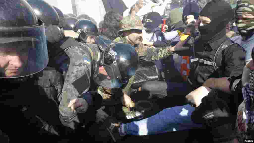 Protesters, right, clash with Interior Ministry and law enforcement members during a rally near the parliament building in Kyiv, Oct. 14, 2014. Thousands of Svoboda nationalist party supporters rallied in Kyiv earlier Tuesday in celebration of the Ukrainian Insurgent Army, but officials from the party denied vehemently that its members were involved in the unrest. 