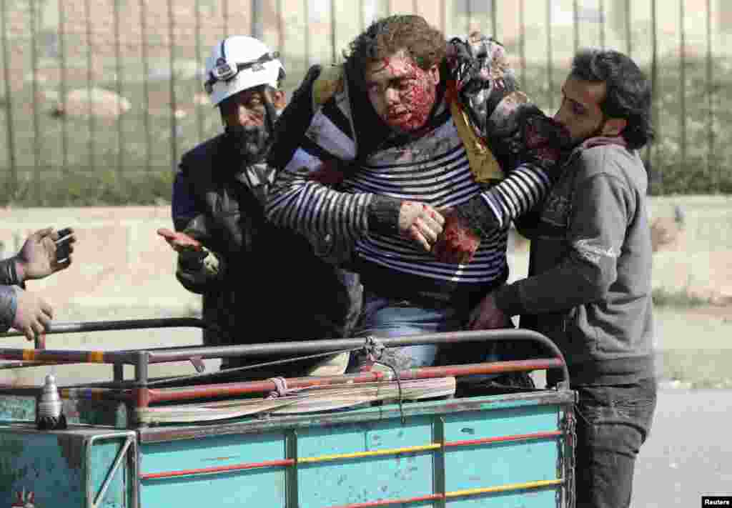 Rescuers help an injured civilian at a site hit by what activists said were barrel bombs dropped by forces loyal to Syria's President Bashar al-Assad in Aleppo's al-Sakhour district, April 2, 2014.