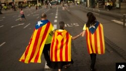 Family members wearing estelada, or independence flags, on their backs walk at the end of a big rally during the Catalan National Day in Barcelona, Spain, Sept. 11, 2017. 