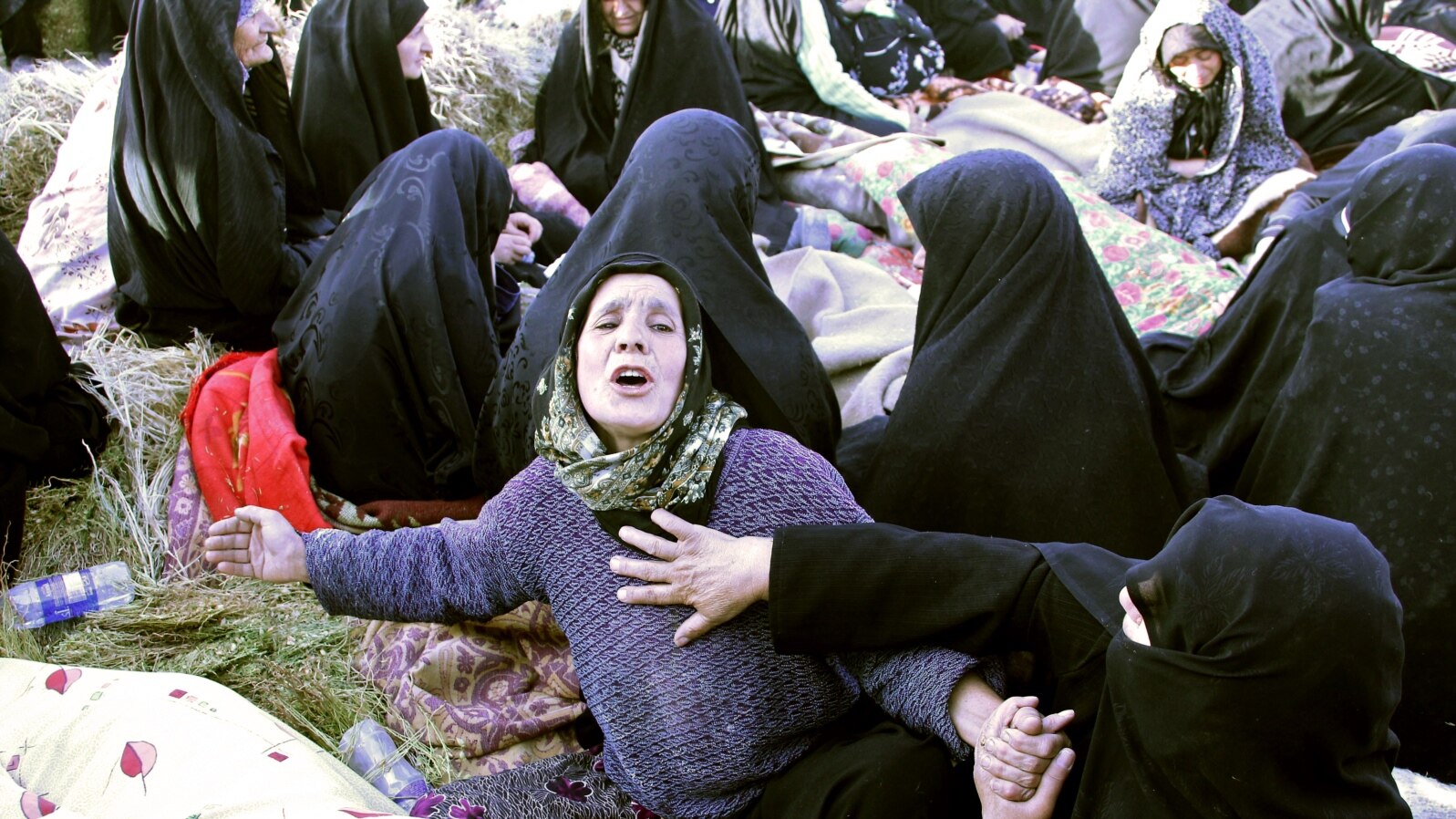  Iranians mourn over the covered bodies of loved ones in the village Baje-Baj, near the town of Varzaqan, who were killed in twin earthquakes that hit northwestern Iran, August 12, 2012.