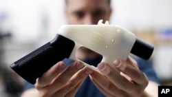 In this Aug. 1, 2018, file photo, Cody Wilson, with Defense Distributed, holds a 3D-printed gun called the Liberator at his shop in Austin, Texas.