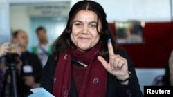 Fawza Youssef, a senior Kurdish politician, shows her ink-stained finger after casting her ballot in Qamishli, Syria, Dec. 1, 2017.