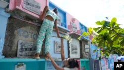 A woman hands over a flower to her daughter as she climbs to reach the tomb of their loved one at Manila's North Cemetery, Philippines, as the nation observes All Saints Day.