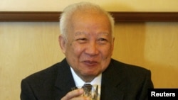 Cambodian King Norodom Sihanouk holds a glass during a meeting with Chinese State Councilor Dai Bingguo (not seen) in Beijing, October 30, 2006.