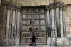 FILE - A woman prays in front of the Church of the Holy Sepulchre in the Old City of Jerusalem following the closure of the city for non-residents as a measure to contain the spread of the novel coronavirus, March 30, 2020.