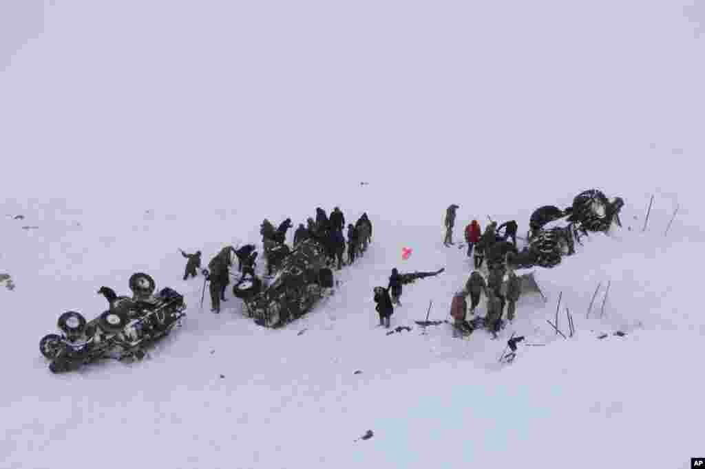 Emergency service members dig in the snow around at least three overturned vehicles, near the town of Bahcesehir, in Van province, eastern Turkey. Some dozens of rescue workers are missing after being hit by a second avalanche.