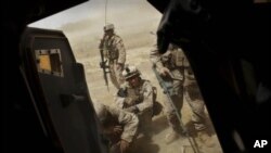 United States Marines from Bravo Company of the 1st Battalion of the 2nd Marines take cover outside their vehicle as a medevac helicopter leaves the scene with a wounded colleague following an IED strike near Musa Qaleh, in northern Helmand Province, sout