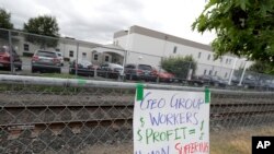 A sign opposing the private contractor that operates the Northwest Detention Center, hangs outside the facility in Tacoma, Wash., July 10, 2018. A man tossed incendiary devices at the center July 13, 2019, and was later found dead.