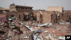 FILE - A man walks by a house hit in fighting in Khartoum, Sudan, an area torn by violence between the military and the notorious paramilitary Rapid Support Forces, April 25, 2023.