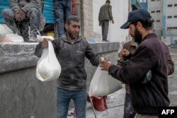 Seorang pria menerima sekantong tepung saat pendistribusian bantuan kemanusiaan di Kota Gaza pada 17 Maret 2024, di tengah pertempuran yang sedang berlangsung antara Israel dan kelompok militan Hamas. (Foto: AFP)