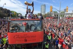 Toronto Raptors guard Kyle Lowry and teammates show off their trophy to fans during a parade through downtown Toronto to celebrate their NBA title, June 17, 2019.