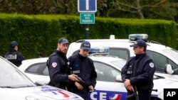 French police officers block the road leading to a crime scene the day after a knife-wielding attacker stabbed a senior police officer to death Monday evening outside his home in Magnanville, west of Paris, June 14, 2016. 