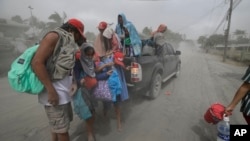 A family evacuates to safer grounds as Taal volcano in Tagaytay, Cavite province, southern Philippines on Monday, Jan. 13, 2020. (AP Photo/Aaron Favila)